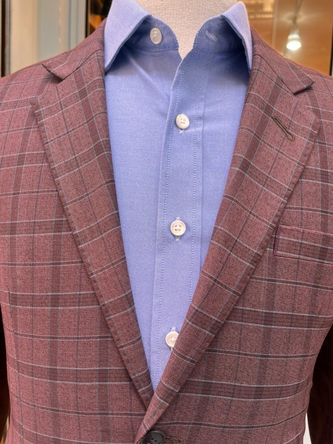 Checkered brick-colored suit jacket with light blue shirt inside, showcasing types of suit lapels and styling for modern business attire