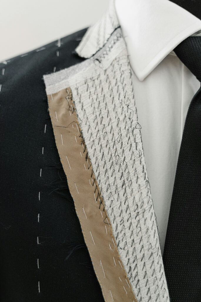 Black full-canvas suit jacket showing hand-stitched internal canvas, fabric